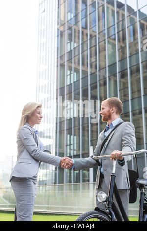 Businesspeople shaking hands outside office building Stock Photo