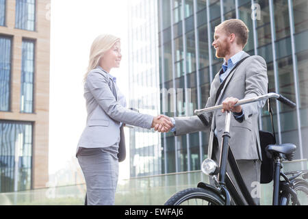 Happy businesspeople shaking hands outside office building Stock Photo