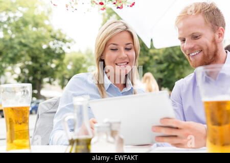 Happy businesspeople using digital tablet at sidewalk cafe Stock Photo