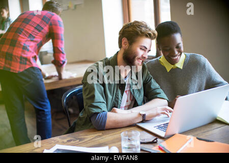 Smiling casual business people working at laptop in office Stock Photo