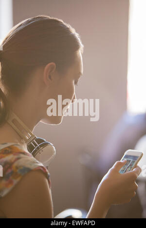 Close up woman with headphones using cell phone Stock Photo