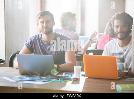 Portrait confident creative businessmen working at laptops in office Stock Photo