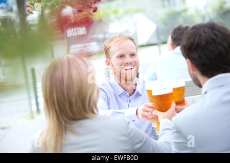 Happy businessman toasting beer glass with colleagues at outdoor restaurant Stock Photo