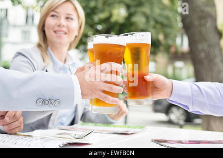 Businesspeople toasting beer glasses at outdoor restaurant Stock Photo