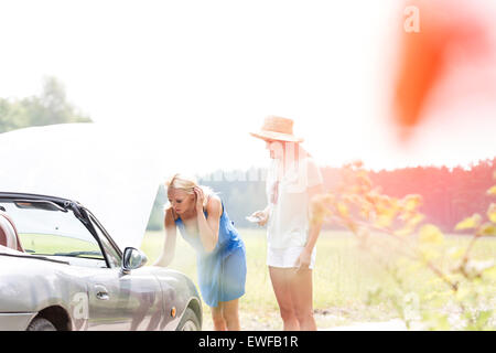 Friends repairing broken down car on sunny day Stock Photo
