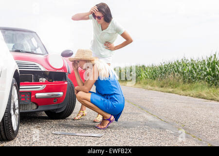 Tensed women looking at damaged cars on road against clear sky Stock Photo