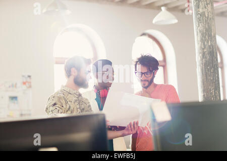 Creative business people reviewing paperwork in sunny office Stock Photo