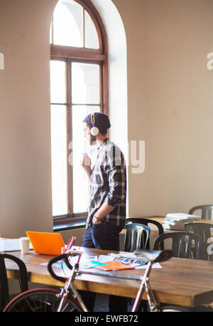 Pensive creative businessman with headphones looking out office window Stock Photo