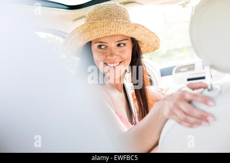 Happy woman looking back while driving car Stock Photo