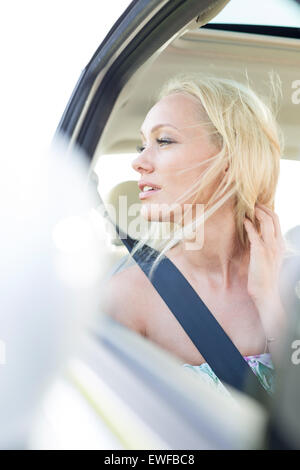 Young woman looking through car window Stock Photo