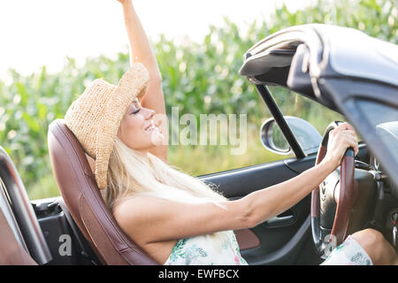 Side view of woman enjoying ride in convertible outdoors Stock Photo