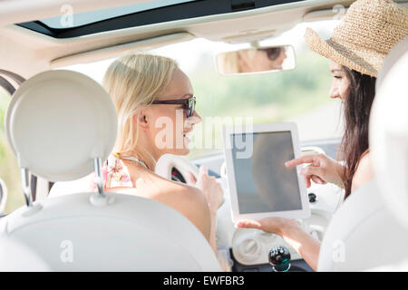 Rear view of happy women using digital tablet in car Stock Photo