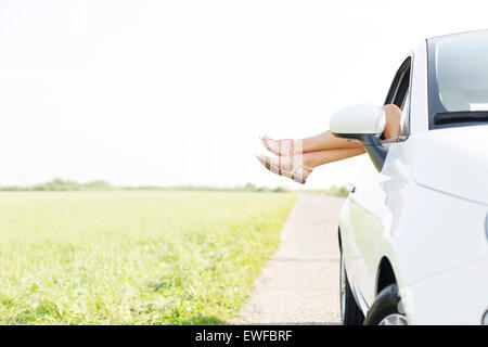 Low section of woman relaxing in car on country road Stock Photo