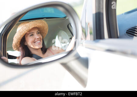 Reflection of happy woman in rearview mirror of car Stock Photo