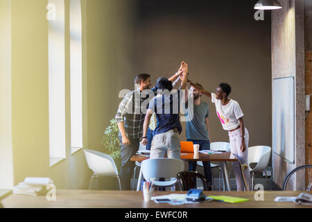 Creative business people joining hands at table in office Stock Photo