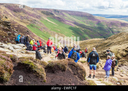 Hikers or walkers resting and viewing the countryside after walking up Grindsbrook Clough, Kinder Scout, Derbyshire, Peak District, UK