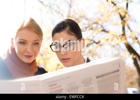 Businesswomen reading newspaper at park Stock Photo