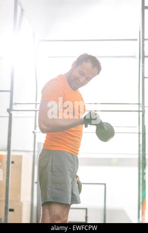 Confident man lifting kettlebell in crossfit gym Stock Photo
