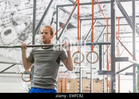 Confident man doing chin-ups in crossfit gym Stock Photo