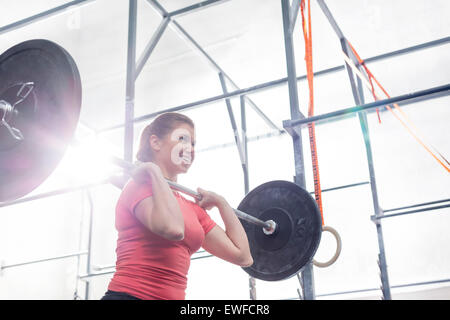 Low angle view of smiling woman lifting barbell in crossfit gym Stock Photo