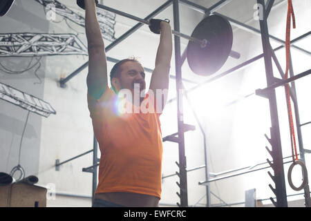 Dedicated man lifting barbell in crossfit gym Stock Photo