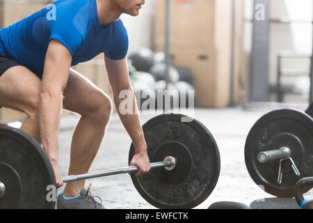 Low section of dedicated man lifting barbell in crossfit gym Stock Photo