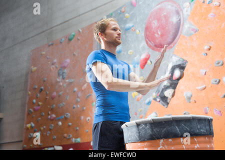 Low angle view of confident man dusting powder by climbing wall in crossfit gym Stock Photo