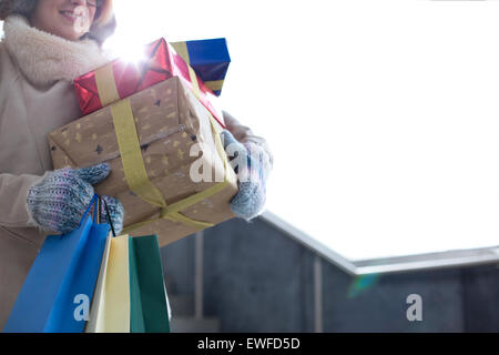 Midsection of woman with stacked gifts and shopping standing by window during winter Stock Photo