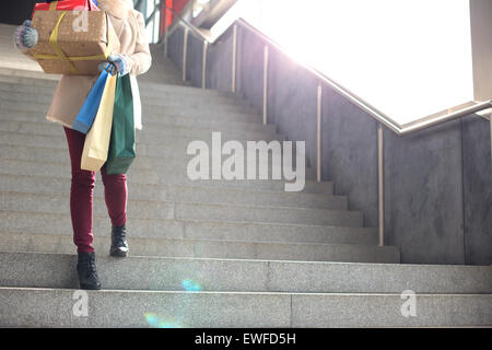Low angle view of woman with gifts and shopping bags moving down steps Stock Photo