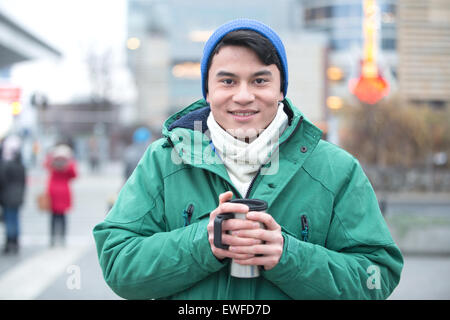 Portrait of man in winter clothing smiling on city street Stock Photo