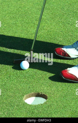 Close up of person putting golf ball on golf course Stock Photo