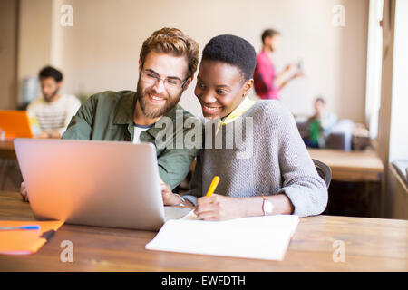 Smiling creative business people using laptop and brainstorming Stock Photo