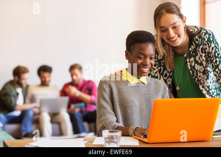 Smiling creative businesswomen working at laptop in office Stock Photo