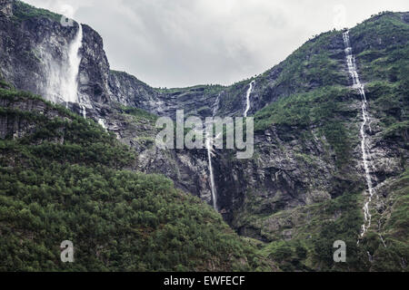 Waterfalls spilling over mountains surrounding Gudvangen, Norway Stock Photo