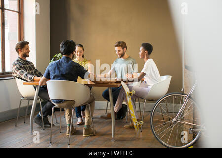 Creative business people holding hands at table in meeting Stock Photo
