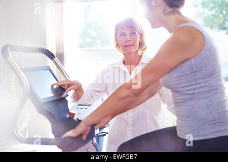 Physical therapy guiding woman on stationary bike Stock Photo