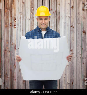 smiling male builder in helmet reading blueprint Stock Photo