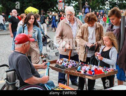 Paris, France - August 9, 2014: Disabled elderly man making small colorful toy gifts near Sacre Coeur Basilica in summer day