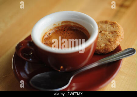 Food Coffee Cafe Espresso beverage served in a demitasse ceramic cup with cookie on the side Stock Photo