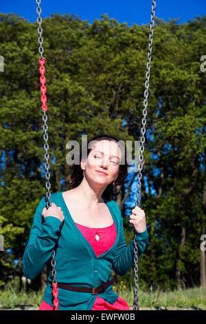 Portrait of brunette lady sitting on swings Stock Photo