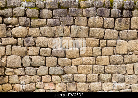 A close-up view of an old, weathered stone wall constructed from irregularly shaped, rough-hewn stones in varying shades of beige, gray, and brown. The stones are tightly fitted together, with some Stock Photo