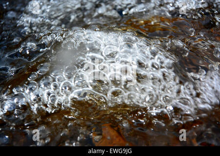 Under surface of a fast flowing river, full of air bubbles, oxygenating the water. Cumbria, UK Stock Photo