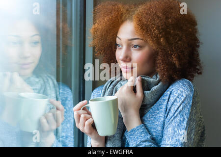 African-American teenage girl drinking tea while sitting on sofa at ...