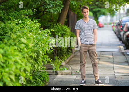 Young man standing on the summer street portrait in full growth. Stock Photo