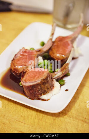 lamb chop plated on a white plate with mash potatoes and pees Stock Photo