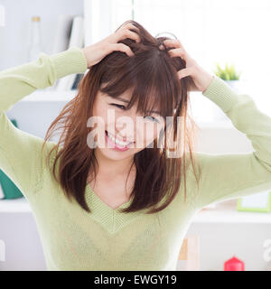 Asian woman scratching itchy head with frustrate face expression, female having hair problems. Stock Photo