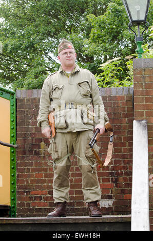 A re-enactor  wearing WW2 US Army GI uniform can carrying an M1 semi-automatic rifle stands guard on a railway footbridge Stock Photo