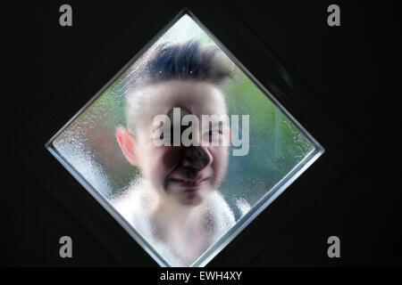 Berlin, Germany, boy looks through the window of a front door Stock Photo