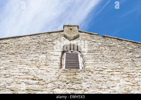Facade of medieval church with window and cross shape in wall Stock Photo