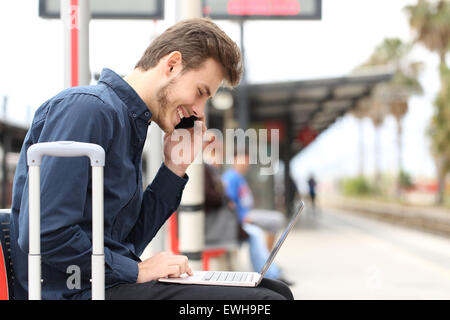 Freelancer working with a laptop and phone in a train station while is waiting for transport Stock Photo